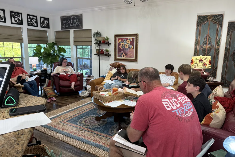A Bible study in a home, students seated around the room